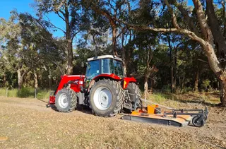 Tractor working beside trees on a property