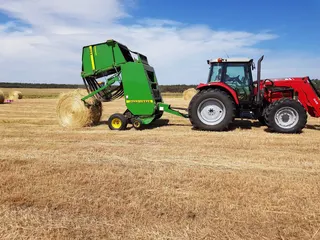 Round baler producing a hay bale in the paddock