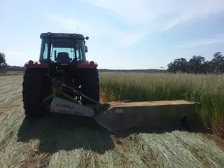 Tractor cutting hay with a front-mounted mower