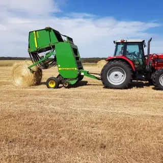 Tractor and round baler with a finished hay bale