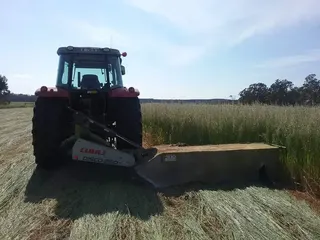 Tractor cutting a hay crop with a front-mounted mower