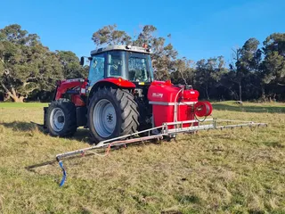 Massey Ferguson tractor fitted with a red spray tank and spray boom